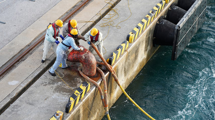  group of people workers in yellow helmets and life jackets moor a cruise ship in the seaport, many people pull a thick rope ashore. Workflow Security