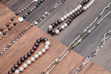 Beautiful handmade necklaces made with various white and brown gemstones on wooden table