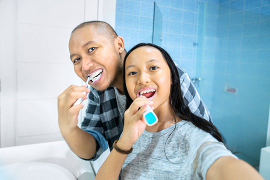 Father and child taking selfie while brushing teeth
