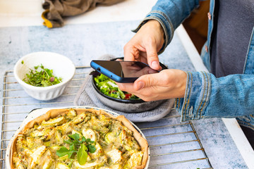 Make picture of vegan food with phone. Smartphone blogging photography of zucchini potato vegetables casserole.