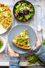 Vegetable casserole or tart with potato and zucchini. Vegan healthy food. Woman hands