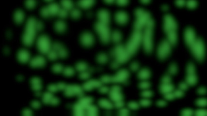 Random motion of particles of green particles in bokeh over black background.