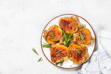 Baked chicken thighs with herbs on white plate.
