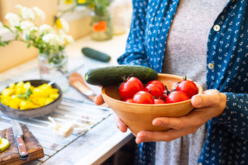 Fresh ripe red cherry tomatoes and green cucumbers vegetables. Vegan organic food. Woman hands