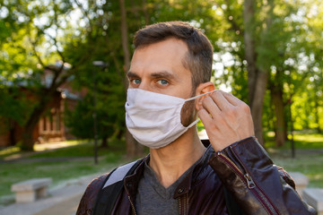 Masked man in the park. A man with a phone walks in the park. covid-19, coronavirus,  pandemic.
