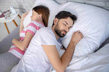 Pregnant young woman in a striped tshirt and her husband sleeping