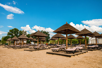 Brown wooden loungers and umbrellas on empty sandy beach. Rows resting places in the failed tourist season.