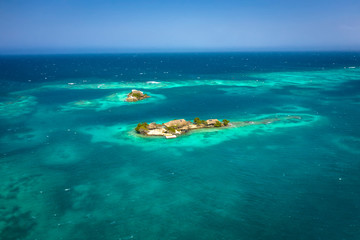 Aerial flying drone view of the sunny tropical paradise island with aqua blue sky sea water ocean. Island with single-family hotel.