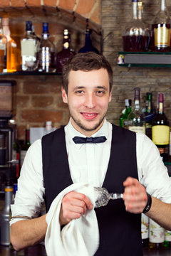 A Young Guy Working As A Bartender Behind A Bar Is Preparing Drinks For Customers.