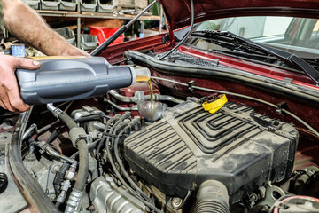 Car mechnic fills engine oil into a car engine