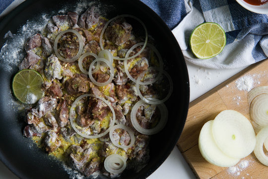 Chicken liver with onion rings in flour and lime with spices 