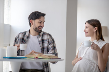 Dark-haired man and his pregnant wife having tea together