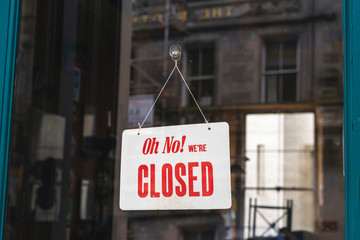 Oh no! We're closed sign board hanging on a door of cafe