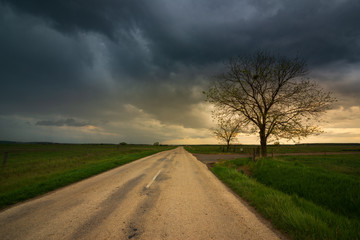 Dark storm clouds over the country road , moody dark sky - 350206359