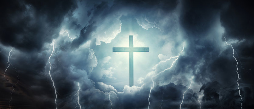 The cross as a symbol of the Christian faith and a stormy sky as a symbol of mortal life full of trials. Concept on the theme God, paradise, religion, Christian faith. Divine light, cross and heaven.