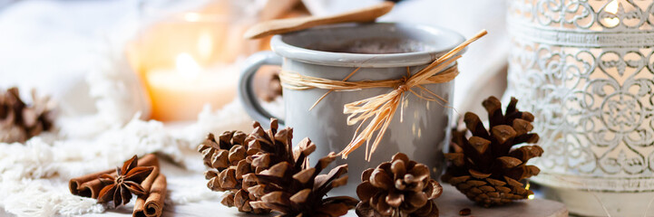 Hot winter drink: hot chocolate in grey mug. Christmas time. Cozy home atmosphere, candle and...