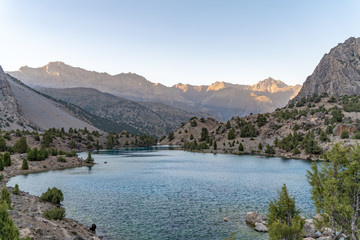 Fototapeta premium The beautiful mountain trekking road with clear blue sky and rocky hills and the view of Alaudin lake in Fann mountains in Tajikistan