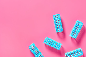 Scattered plastic cylindrical curler on pink desk in beauty salon. Care for hair. Fashion concept. Top view
