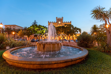 View of fountain in front of the Town Hall of Ciutadella at evening with illumination.