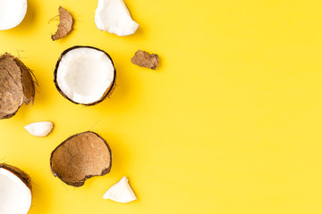 Coconut pieces on yellow background with copyspace. Flat lat. Top view