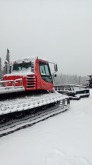 Red winter ratrak parked in slope in the snow