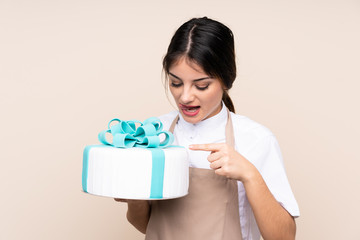 Pastry chef woman holding a big cake over isolated background