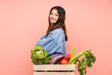 Young farmer woman holding a basket full of fresh vegetables laughing