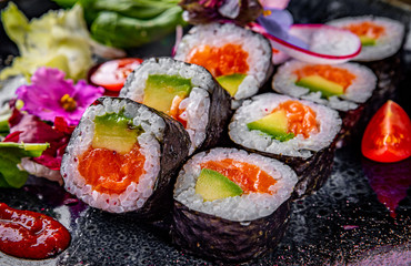 sushi roll with salmon, avocado, rice in plate