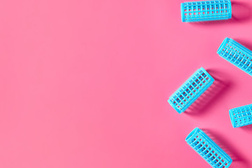 Scattered plastic cylindrical curler on pink desk in beauty salon. Care for hair. Fashion concept. Top view