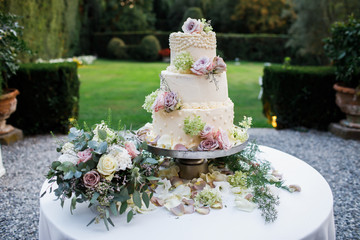 Wedding cake standing on the table. Around the flowers.