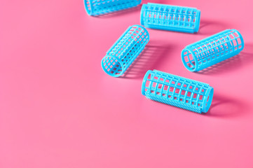 Scattered plastic cylindrical curler on pink desk in beauty salon. Care for hair. Fashion concept