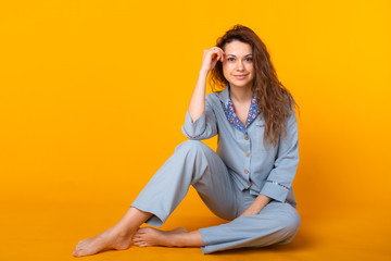 Young girl posing in pajamas on yellow background. Relax good mood, lifestyle and sleepwear concept.
