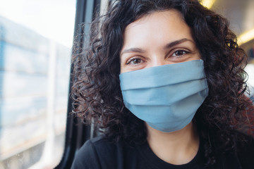 Close up portrait of a smiling woman in medical mask in a train. Concept of the end of the lockdown