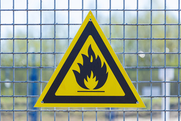 Black caution or warning fire triangle sign on yellow background or table on the painted grill of...