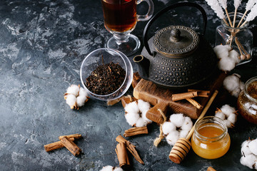 A black metal teapot and a cup of tea in glass cup