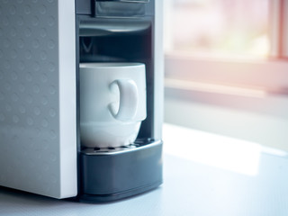 White ceramic coffee cup on coffee machine.