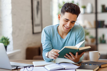 Cheerful ethnic student reading book.