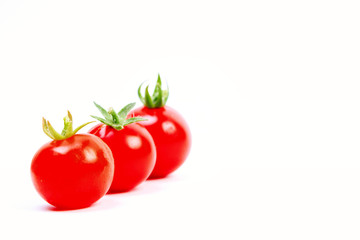 three red cherry tomatoes on a white background