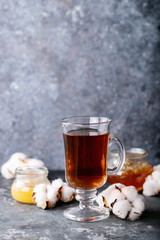 A black metal teapot and a cup of tea in glass cup