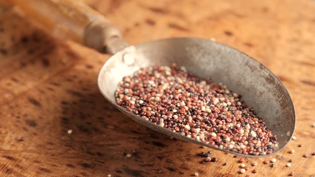 Black raw quinoa in old metal spoon rotating, South American grain. Healthy and gluten free food concept background.