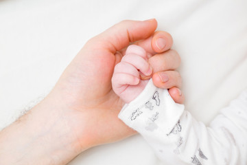 Young father and infant hands together. Lovely, emotional, sentimental moment. Safety concept. Closeup. Top down view.