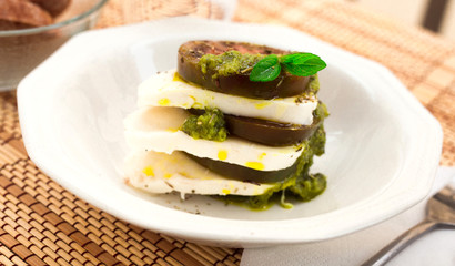 caprese salad with mozzarella, black tomatoes and pesto in white plate