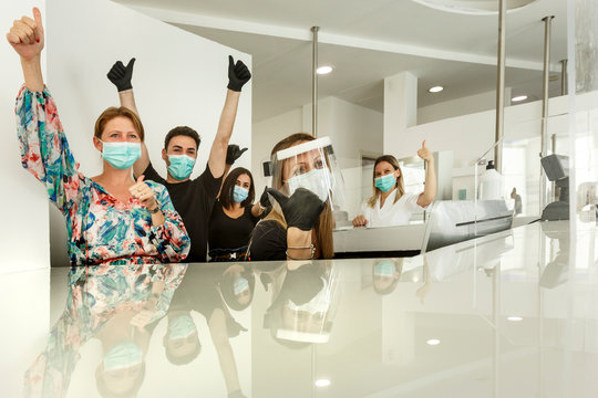 gruppo affiatato di lavoro con in primo piano la segretaria fornita di tutti i dispositivi di protezione e il resto della squadra con mascherina chirurgica
