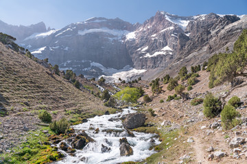 The beautiful mountain trekking road with clear blue sky and rocky hills and fresh mountain stream in Fann mountains in Tajikistan