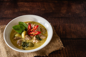 Green curry with fish ball in bowl as traditional Thai food and serve with steamed rice on old wooden background
