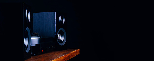 Vintage audio speakers, turntable and vinyl records on a dark background