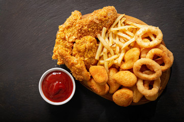 fast food meals : onion rings, french fries, chicken nuggets and fried chicken, top view