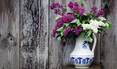 Fototapeta na wymiar vase with a bouquet of multi-colored lilacs. White vase with a blue pattern. Background old wood. Retro style Concept. Copy space.
