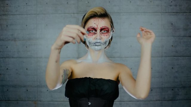 Nice girl with body art tattoo patterned skull chicano style on her face looking at the camera. Halloween party and mexicans death day santa muerte concept
