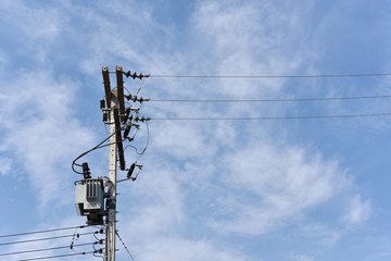 Energy and technology: electrical post by the road with power line cables, transformers against...